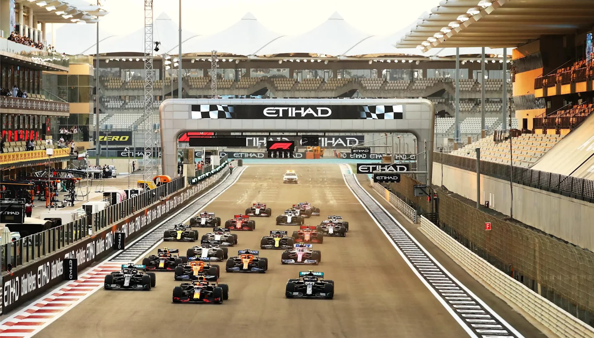 Formula 1 cars lined up on the grid at the start of a race under the Etihad arch